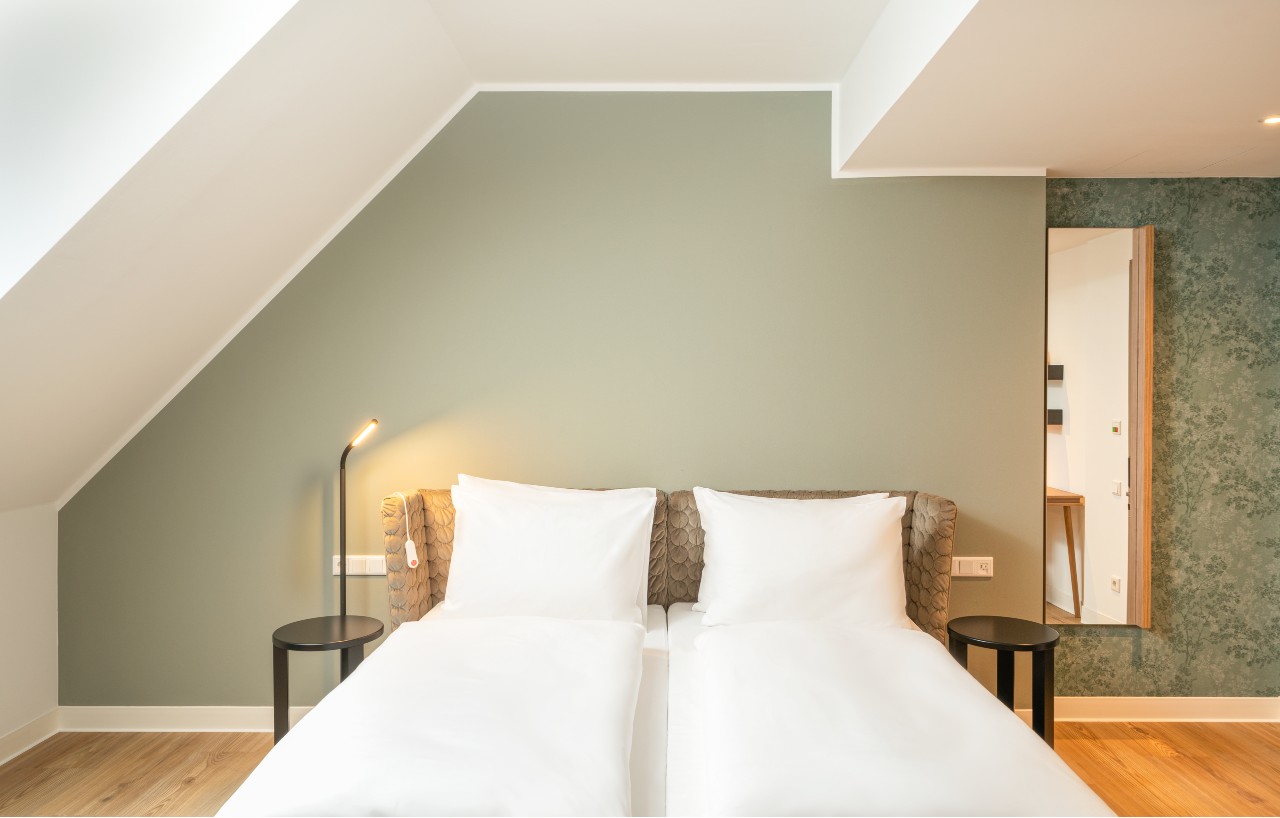 elaya-hotel-regensburg-city-center-behindertengerechtes-doppelzimmer-gruen Platz für zwei bietet das Doppelbett im barrierefreien Doppelzimmer im elaya hotel regensburg city center