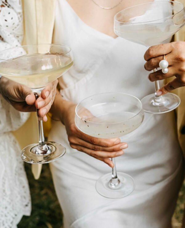 Women wearing summer dresses, holding glasses of champagne at a