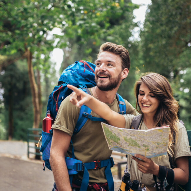 Couple hiking trough forest. Using map to get good direction.