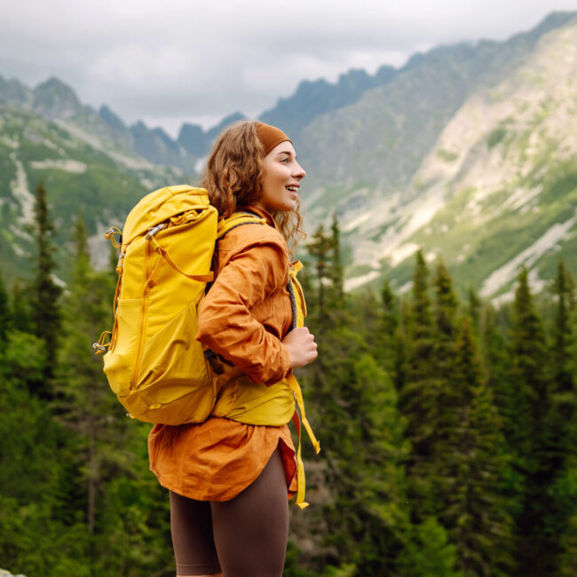 An active female traveler with a bright hiking backpack enjoys t