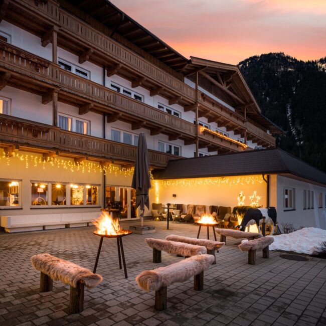 kuhotel-by-rilano-waidring-aussenansicht-lagerfeuer Cosy atmosphere with a campfire at elaya hotel steinplatte